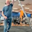 Smiling older man performing a landmine press in a gym, demonstrating strength, movement, and vitality at Focus Health & Fitness.
