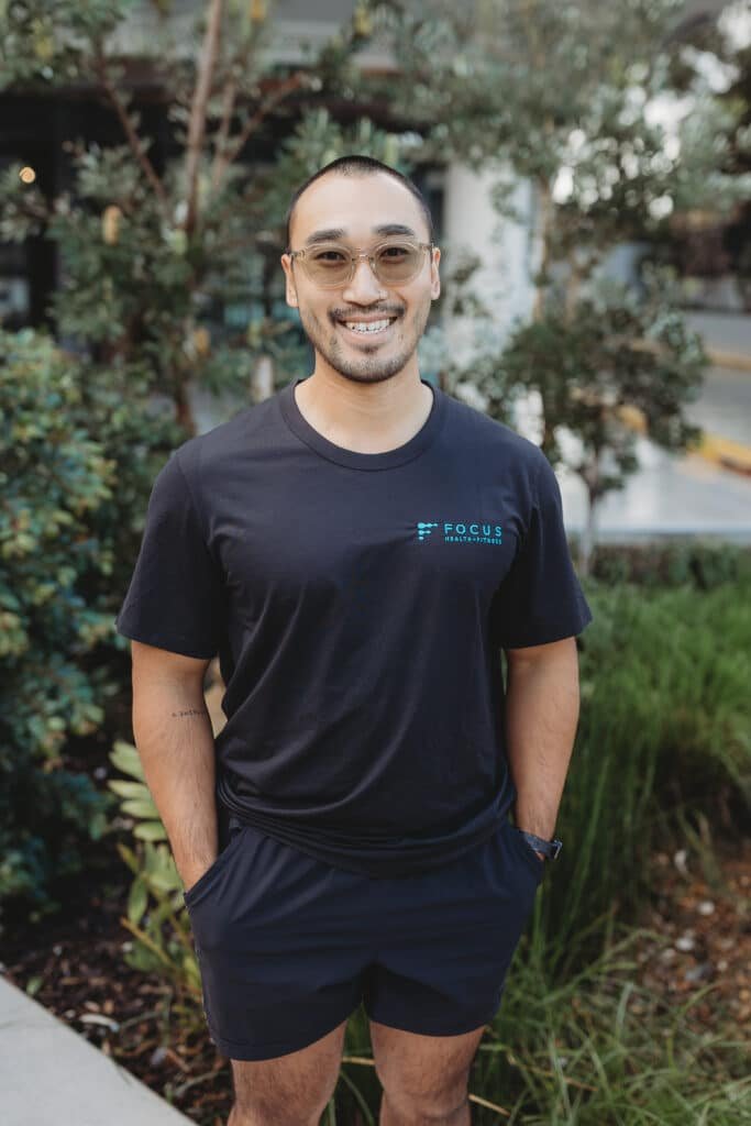James, personal trainer at Focus Health & Fitness Norwest, standing outside the studio smiling in a team t-shirt.