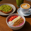 Healthy café meal with avocado toast, smoothie bowl, green juice, and latte on a wooden table in the Hills District.
